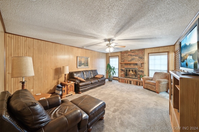 carpeted living room featuring ceiling fan, crown molding, a textured ceiling, and a brick fireplace