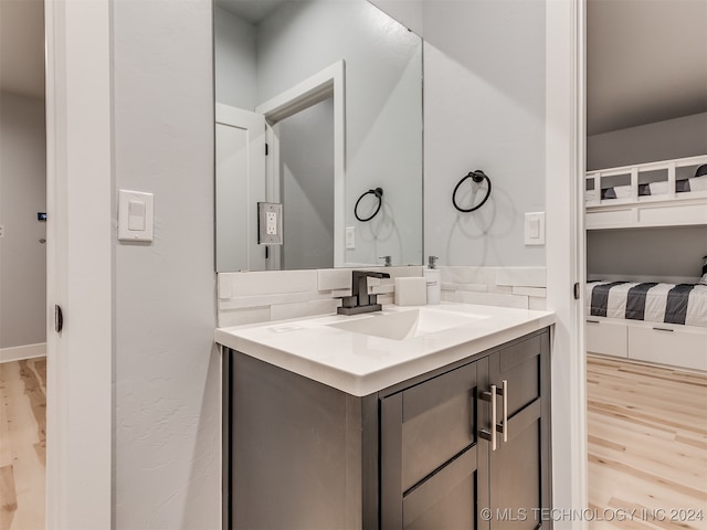 bathroom with vanity, hardwood / wood-style floors, and decorative backsplash