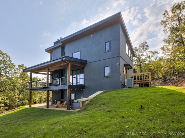 back of property featuring a balcony, cooling unit, a patio area, and a lawn