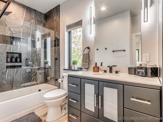 full bathroom featuring vanity, combined bath / shower with glass door, hardwood / wood-style floors, and toilet