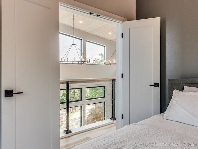 bedroom featuring an inviting chandelier, hardwood / wood-style flooring, and wood ceiling