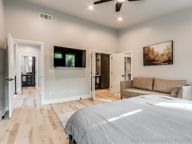 bedroom with a spacious closet, a closet, ceiling fan, light hardwood / wood-style floors, and a high ceiling