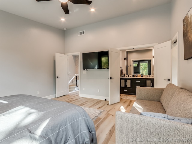 bedroom featuring a high ceiling, light wood-type flooring, and ceiling fan