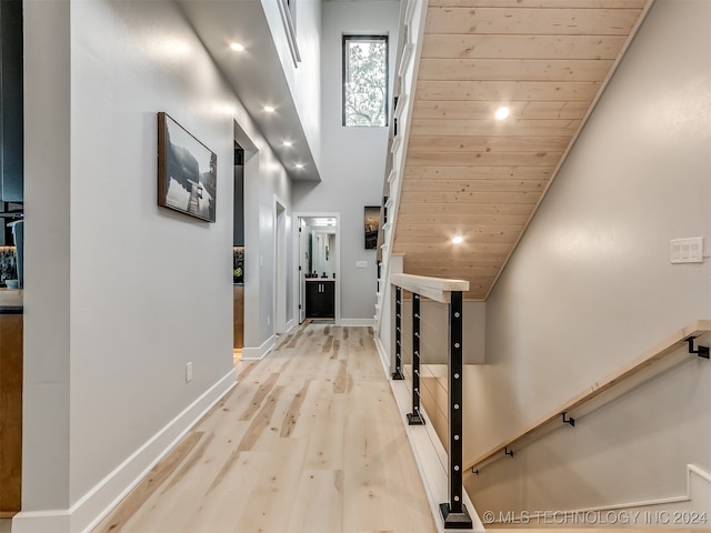 corridor featuring wood ceiling, high vaulted ceiling, and light wood-type flooring