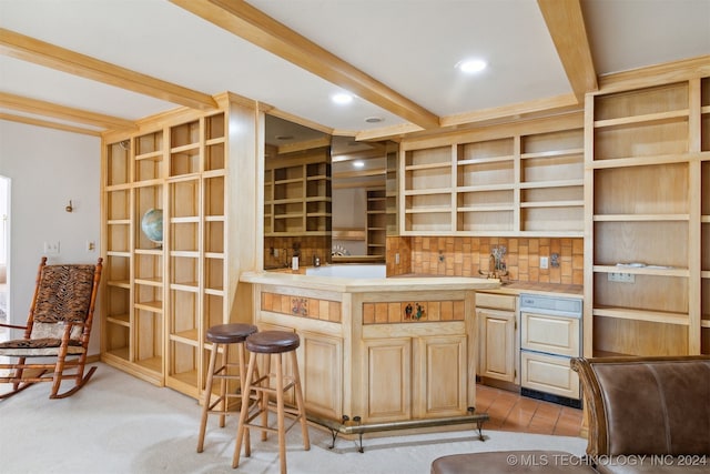 kitchen featuring a kitchen bar, beamed ceiling, decorative backsplash, light brown cabinets, and light colored carpet