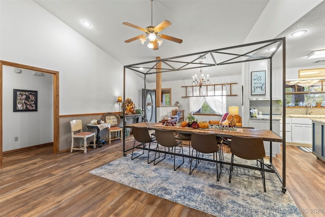 dining space with high vaulted ceiling, sink, ceiling fan with notable chandelier, and light wood-type flooring