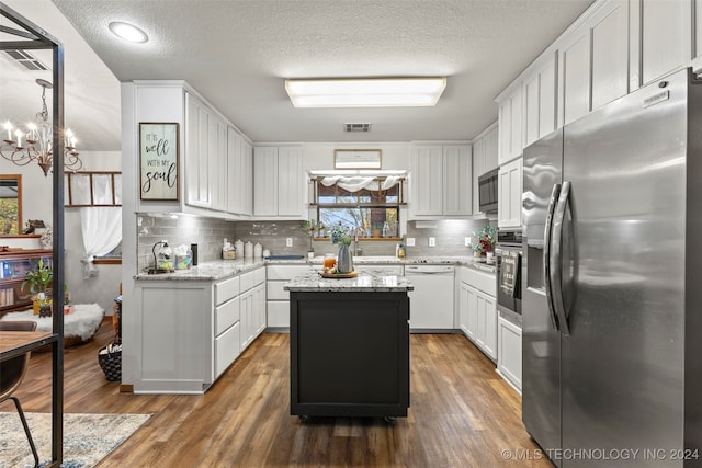 kitchen with white cabinetry, light stone countertops, stainless steel appliances, and a kitchen island