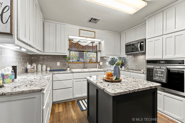 kitchen featuring dark hardwood / wood-style flooring, appliances with stainless steel finishes, a center island, and white cabinets