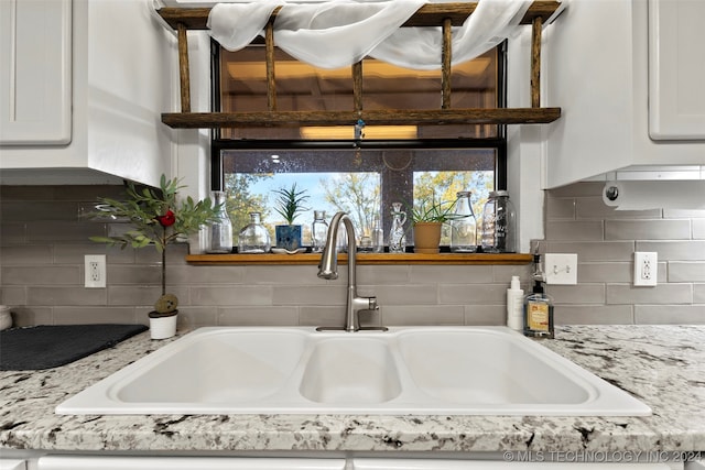 details featuring light stone countertops, sink, and white cabinets