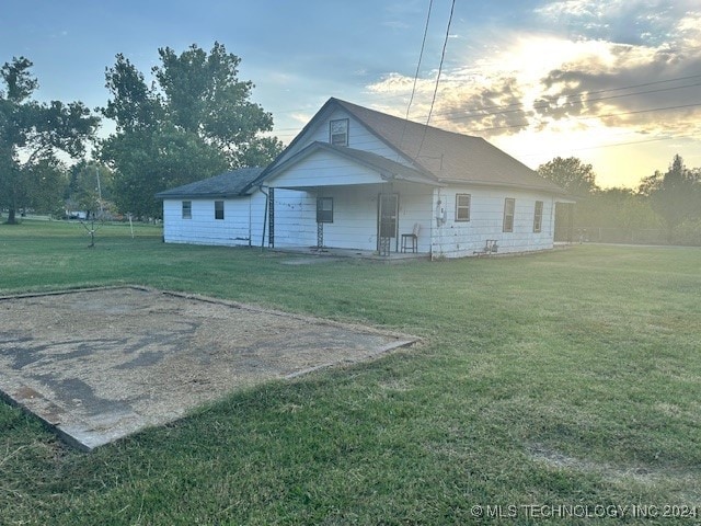 back house at dusk with a lawn