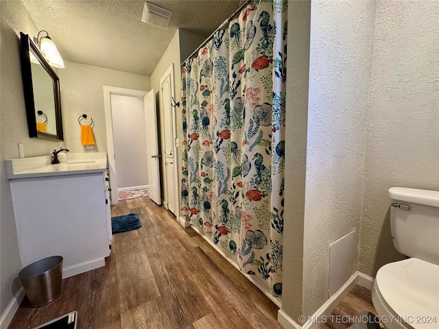 bathroom featuring hardwood / wood-style flooring, vanity, a textured ceiling, and toilet