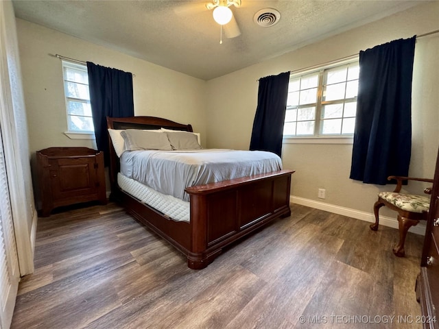 bedroom featuring dark wood-type flooring, ceiling fan, and a textured ceiling