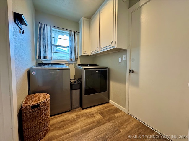 laundry room featuring cabinets, washer and clothes dryer, and light wood-type flooring