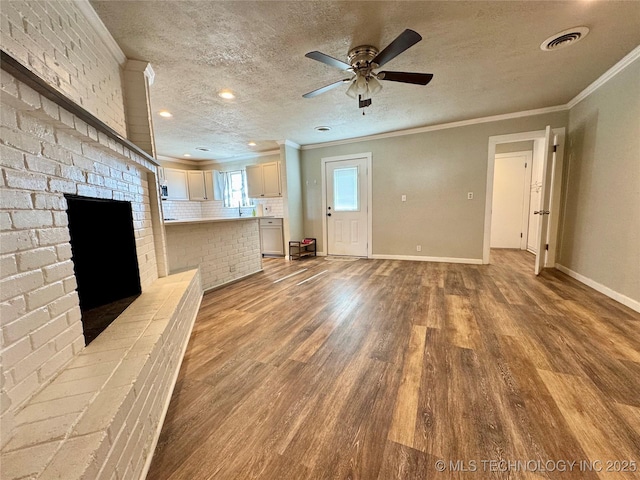 unfurnished living room with a textured ceiling, light wood-type flooring, ornamental molding, ceiling fan, and a fireplace