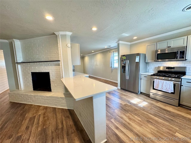 kitchen featuring a breakfast bar, stainless steel appliances, kitchen peninsula, and light wood-type flooring