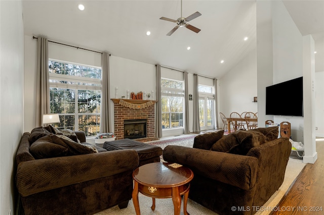 living room with high vaulted ceiling, a fireplace, ceiling fan, and light wood-type flooring