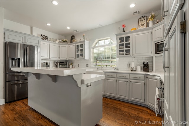 kitchen featuring dark hardwood / wood-style flooring, a center island, built in appliances, sink, and white cabinetry