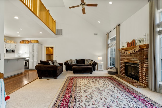 living room with high vaulted ceiling, light wood-type flooring, a healthy amount of sunlight, and a fireplace