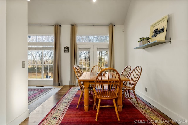 dining area with hardwood / wood-style floors, plenty of natural light, and vaulted ceiling