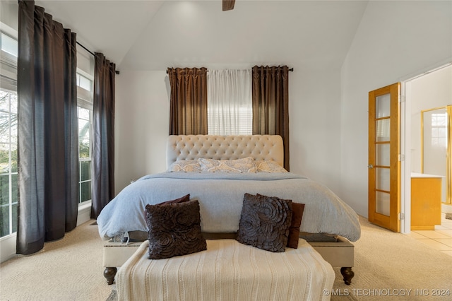 bedroom featuring ensuite bath, lofted ceiling, and light carpet