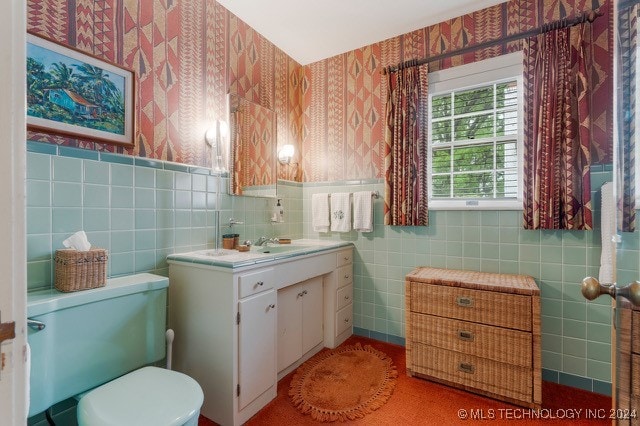 bathroom featuring toilet, vanity, and tile walls