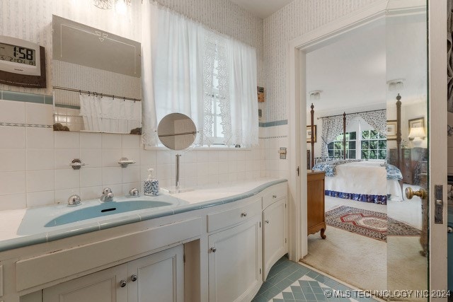 bathroom featuring tile walls, tasteful backsplash, vanity, and a healthy amount of sunlight