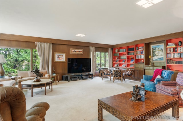 carpeted living room featuring wood walls, a wealth of natural light, and built in shelves