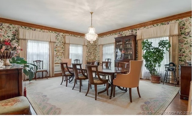 carpeted dining area with a notable chandelier and ornamental molding