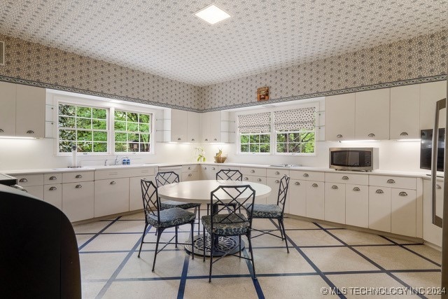 kitchen featuring a wealth of natural light and white cabinets