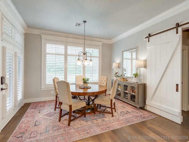 dining room featuring crown molding, a barn door, dark hardwood / wood-style floors, and an inviting chandelier