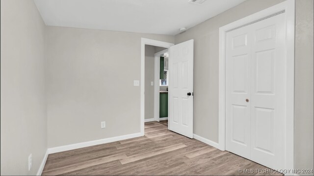 unfurnished bedroom featuring light hardwood / wood-style floors and a closet