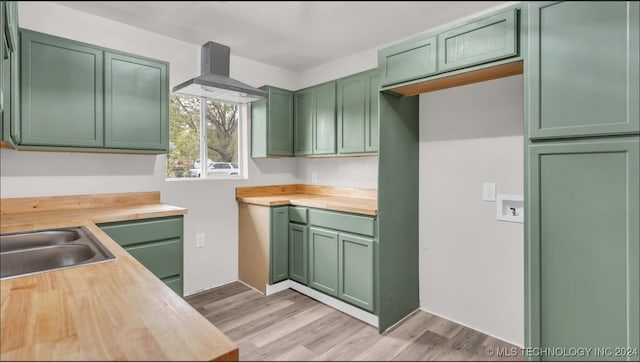 kitchen featuring sink, extractor fan, green cabinetry, light hardwood / wood-style flooring, and butcher block countertops