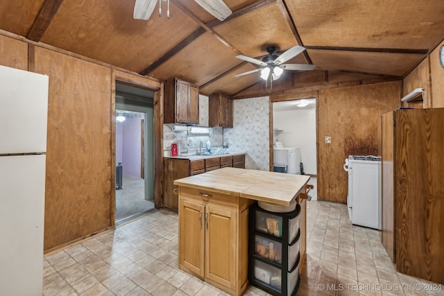 kitchen with washer / dryer, ceiling fan, vaulted ceiling, tile counters, and white appliances