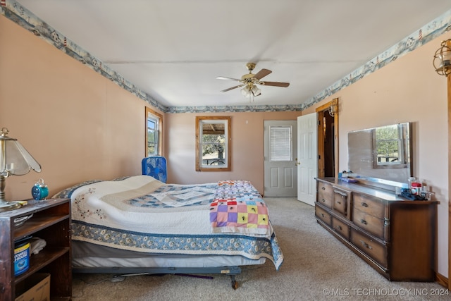 bedroom featuring ceiling fan, multiple windows, and light colored carpet