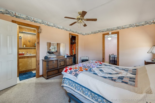 carpeted bedroom with a spacious closet, ensuite bath, a closet, ceiling fan, and heating unit