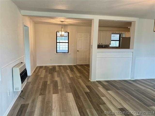 unfurnished living room with a healthy amount of sunlight, heating unit, and dark hardwood / wood-style floors