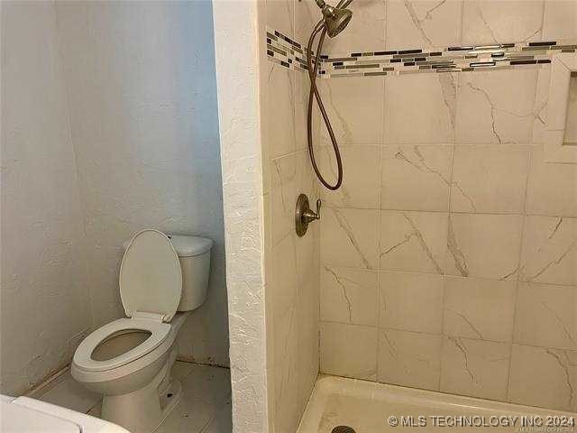 bathroom featuring a tile shower and toilet