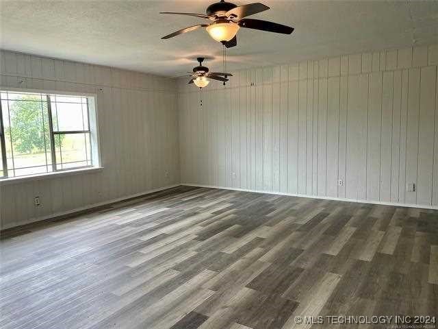 empty room with ceiling fan, hardwood / wood-style flooring, and wood walls