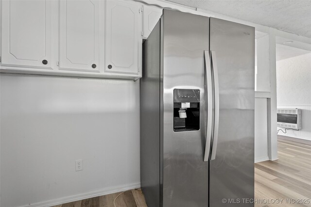 7740 Swayback, Sulphur, OK 73086 - kitchen view of stainless steel refrigerator with ice dispenser, heating unit, light wood finished floors, and white cabinets