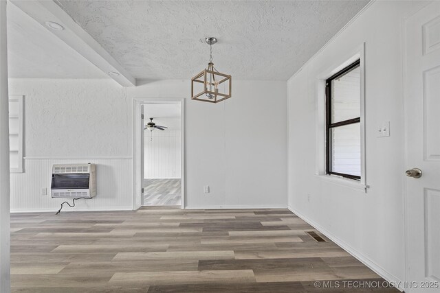 7740 Swayback, Sulphur, OK 73086 - unfurnished dining area with heating unit, a chandelier, wood finished floors, a textured ceiling, and ceiling fan