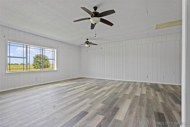 7740 Swayback, Sulphur, OK 73086 - spare room with wood finished floors, a ceiling fan, a textured ceiling, and wood walls