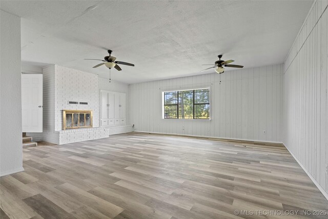 7740 Swayback, Sulphur, OK 73086 - unfurnished living room with a ceiling fan, light wood-style floors, a textured ceiling, and a brick fireplace