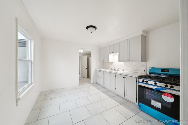 kitchen with white cabinetry, ornamental molding, stainless steel gas range, and decorative backsplash