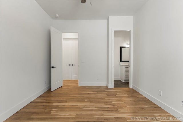 unfurnished bedroom featuring ensuite bathroom, light hardwood / wood-style floors, and ceiling fan