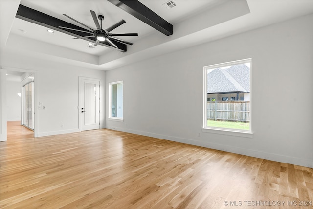 empty room with beamed ceiling, light hardwood / wood-style floors, and ceiling fan