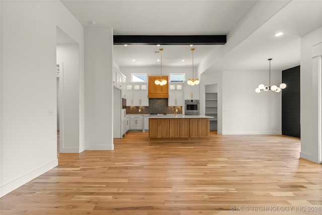 kitchen featuring oven, white cabinets, a kitchen island, and pendant lighting