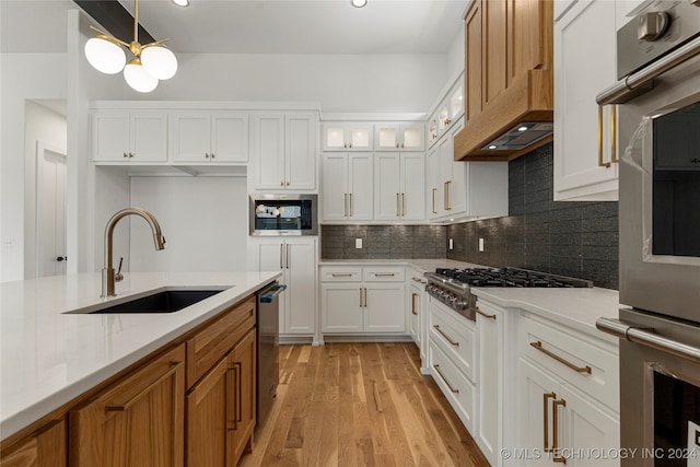 kitchen featuring appliances with stainless steel finishes, white cabinets, sink, and light hardwood / wood-style floors