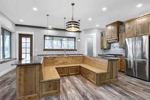 kitchen with stainless steel appliances, an inviting chandelier, dark hardwood / wood-style floors, pendant lighting, and dark stone countertops