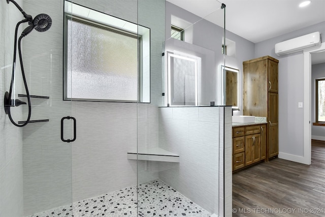 bathroom featuring walk in shower, wood-type flooring, vanity, and a wall mounted air conditioner