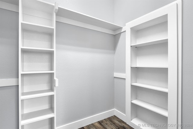 walk in closet with dark wood-type flooring